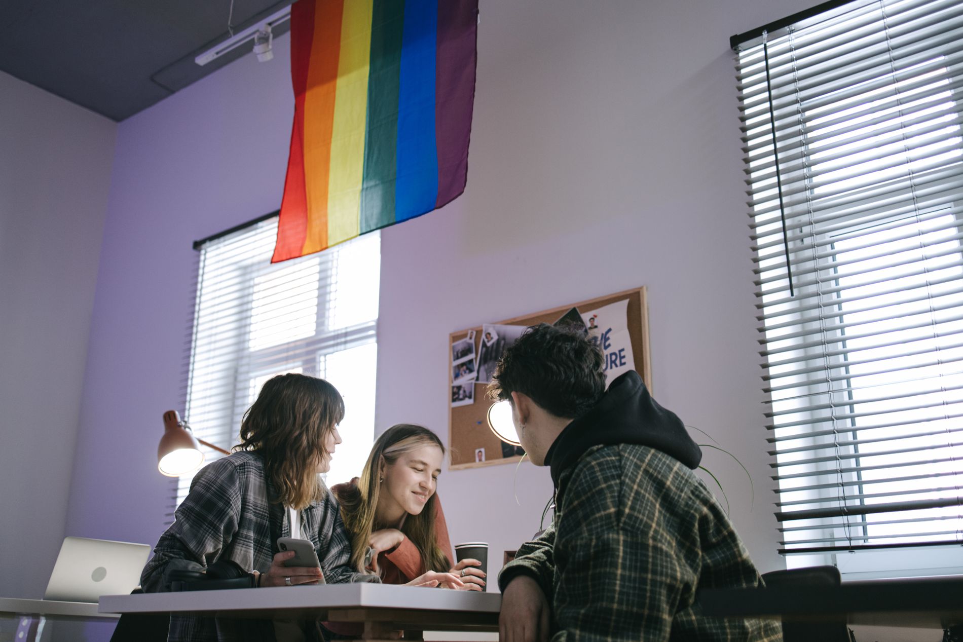LGBTQ+ founders meeting under a Pride flag